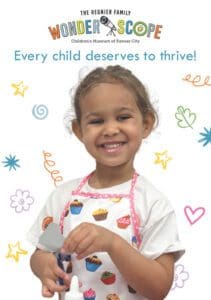 young girl smiling holding paper and scissors