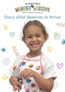 young girl smiling holding paper and scissors